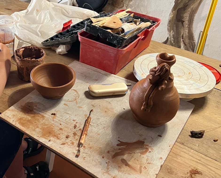 Table de modelage avec bol tourné, pichet décoré et outils de céramiste