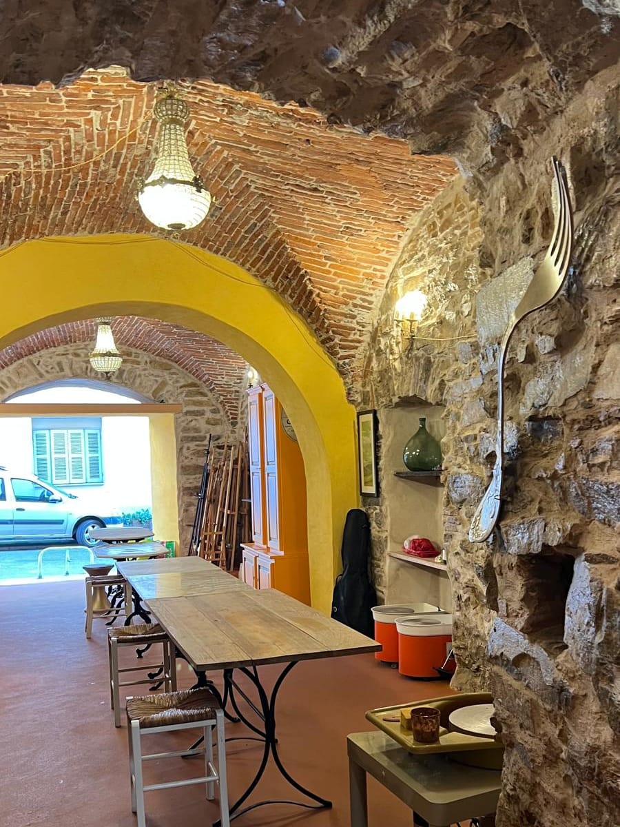 Salle voûtée en pierre de l'atelier, avec grande table de travail et chevalets