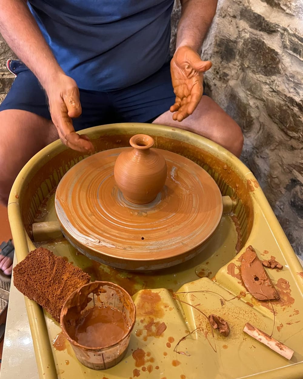 Potier façonnant un petit vase de terre rouge sur un tour